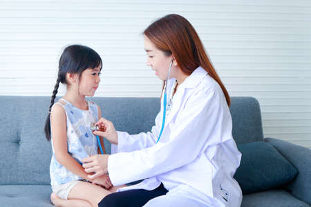 Asian beautiful woman doctor holding a stethoscope to check the pulse, heart rhythm of a cute little...