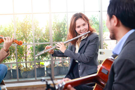 A group of Asian musicians playing classical instruments, flute, violin and guitar. They play classical music. The concept of learning classical music. Live music and bandsの写真素材