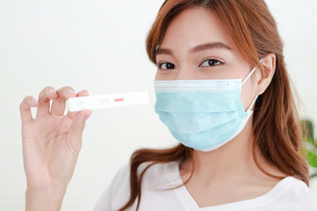 beautiful asian woman She was wearing a blue mask. She is sick with the flu, stays at home and tests herselfの写真素材