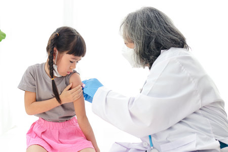 Doctors inject antiviral vaccine to cute little Asian girl with pigtails. Sit on the white bed. concept of vaccination for childrenの写真素材