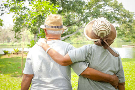 Asian elderly couple hugging each other in the outdoor park The couple enjoyed their vacation....