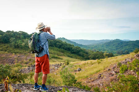 Elderly Asian man hiking Standing on a high mountain looking at the beautiful natural scenery. The concept of natural tourism in retirement age. Copy spaceの写真素材