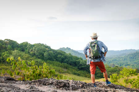 Elderly Asian man hiking Standing on a high mountain looking at the beautiful natural scenery. The concept of natural tourism in retirement age. Copy spaceの写真素材