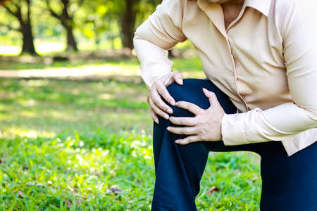 elderly woman walking in the park She had severe knee pain. osteoarthritis concept Knee inflammation in the elderly. health care. copy spaceの写真素材