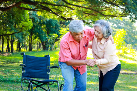 an elderly man in a wheelchair relaxing in the garden He tried to get up and walked, he had severe knee pain. His wife takes care of him. The concept of caring for osteoarthritis patients.の写真素材