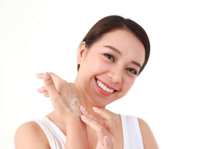 Beautiful Asian woman applying skin cream on her arm to enhance her beauty. She takes care of her skin health to be smooth, bright, healthy, natural. beauty concept health care. White background.の写真素材
