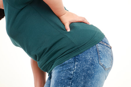 obese woman with back pain She put her hand on the back of the painful area. overweight concept resulting in faster deterioration of herniated discs. white backgroundの写真素材