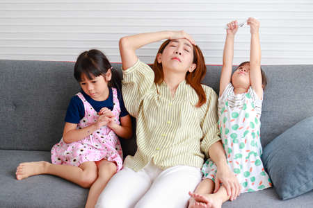Asian single mom Headache raising two mischievous little children. The three of them sat on the sofa...