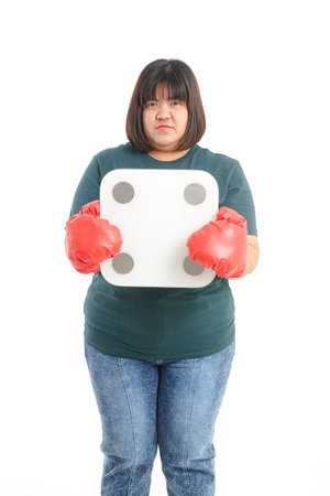 Fat woman wearing red boxing gloves She stood holding a weighing scale. standing on a white background. The concept of being overweight. Exercise to lose weight. white backgroundの写真素材