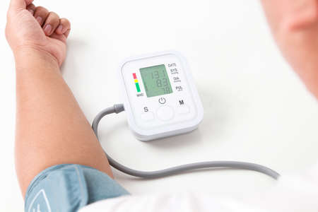 An obese man uses a blood pressure monitor on his arm himself. obesity concept The risk of high blood pressure, diabetes, high blood lipids coronary heart disease. health careの写真素材