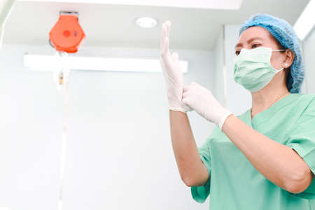Nurse assistant surgeon in operating room Wear gloves and a mask and a apron. In the operating room in the hospital. Concept of medical services. cosmetic surgery. Copy spaceの写真素材