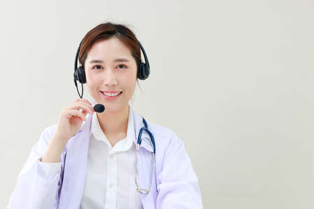 Asian female doctor smiling beautifully Providing treatment services for patients with online conversations via the Internet on laptop computers. online doctor concept. Copy spaceの写真素材