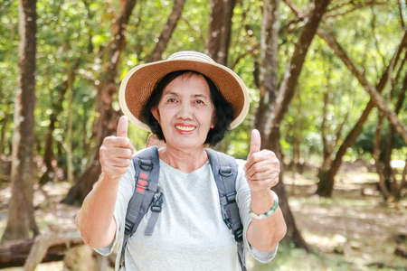 Asian elderly women trekking to travel Thumbs up to be happy. Tourism concept of the elderly in retirement age. health care and exerciseの写真素材