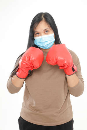 An obese Asian woman wearing a mask and wearing red boxing glovesの写真素材