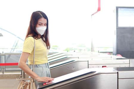 Concept of traffic and transportation. Asian female passengers wearing masks Automatic scanning to the skytrain station in the city. life in the capital cityの写真素材