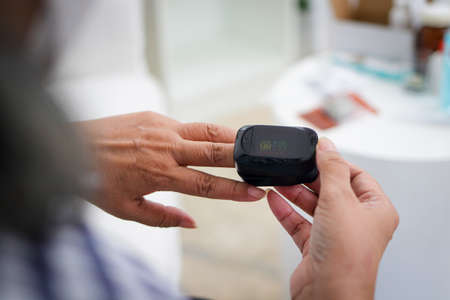 An elderly woman measures fingertip oxygen by herself.の写真素材