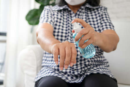 Asian elderly women wearing white masks Spray alcohol on your hands to clean and prevent the virus. The concept of patients staying at home.の写真素材