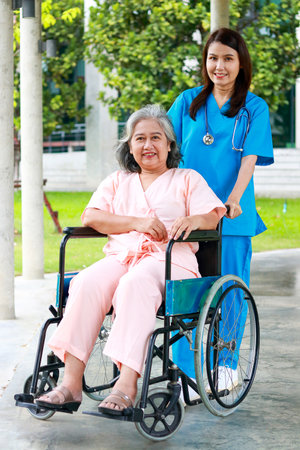 Concept of medical services in hospitals. Patient care. female doctor wearing surgical gown Treat and care for an elderly patient who sits in a wheelchair.の写真素材