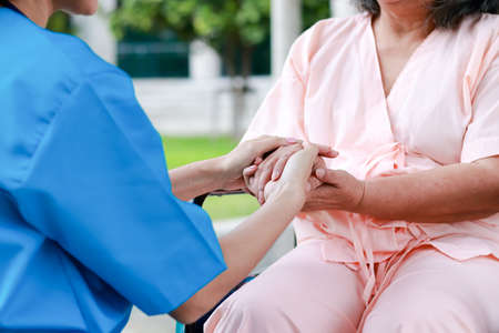 Doctors wearing surgical gowns, holding hands, elderly patients sitting in wheelchairs encouraging, do not worry about treatment. concept of medical services in a hospitalの写真素材