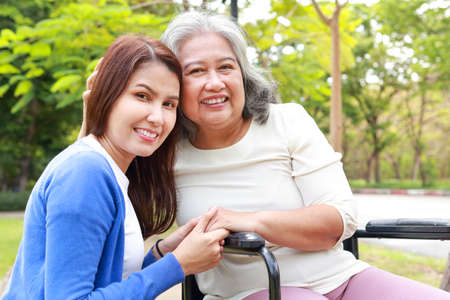Elderly mother and daughter smiling happily in the park in the morning. Family concept. Health care for the elderly in retirement age. Nurses take care of the elderly. Close-up photo.の写真素材