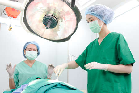 Professional team of Asian surgeons Perform surgery on a patient lying on a bed in a hospital...