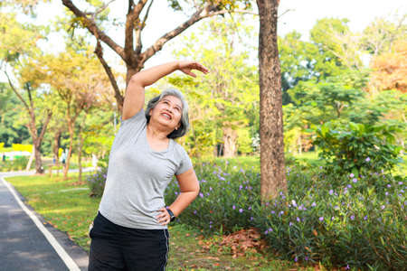 Asian elderly woman exercise in the park in the morning she smiles happy Healthy body. concept of health care for seniors to be healthyの写真素材