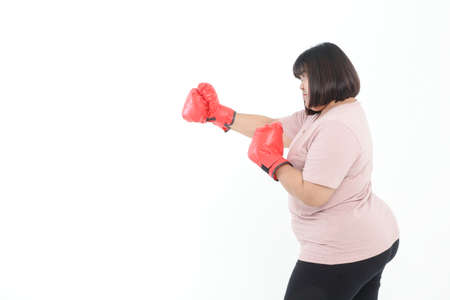 Fat Asian woman wearing red boxing gloves exercising on white background. Concept of exercise,...