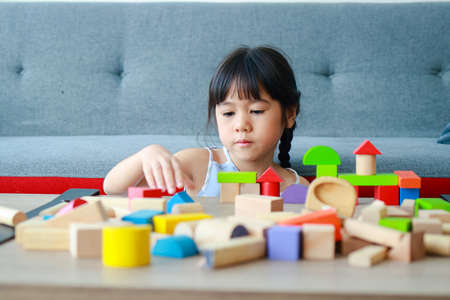 cute little asian girl Smiling happy playing with wooden toys. concept of learning and developing...