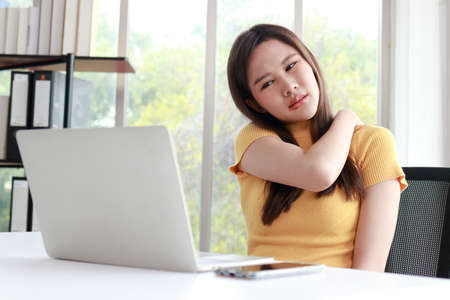 Asian woman working on a computer in the office She had pain in the shoulder muscles due to sitting...