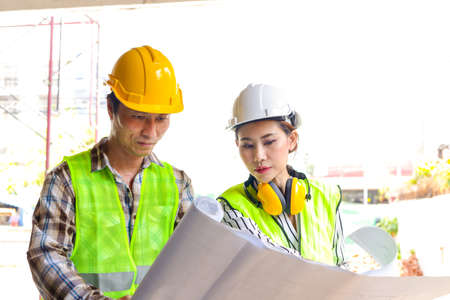 Engineers and construction contractors Holding a blueprint discussing building construction plans at the outdoor site. Real estate project concepts, building construction cooperation.の写真素材