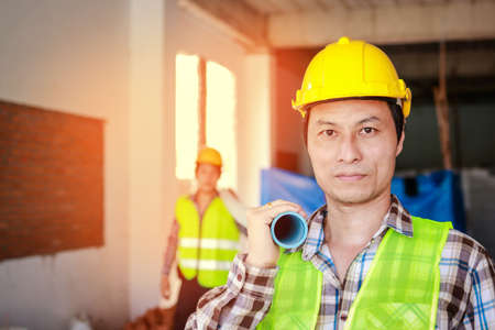 construction worker wearing a yellow helmet Hold the working equipment on the project site. Real estate project concept. Urban development. building construction technologyの写真素材