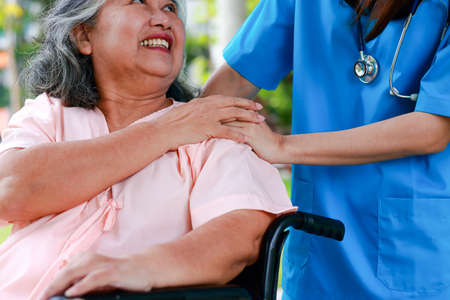 Asian female doctor treats an elderly patient sitting in a wheelchair. Concept of medical services in hospitals. surgical treatment of patientsの写真素材