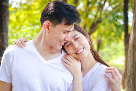 Asian couple wearing white shirts Happy smiling in the park. Family concept. Healthy health care. outdoor exerciseの写真素材