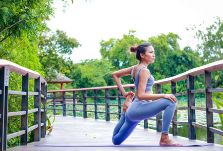 Asian woman exercising outdoors in the garden She is doing stretching yoga. sports concept exercise for good healthの写真素材
