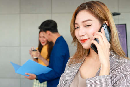 Young Asian businesswoman holding a smartphone talking to a customer. Entrepreneurial concept. Startup business of the new era. working age with health careの写真素材