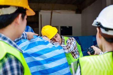 engineer holding a radio to report the work of a construction worker sleeping on the job site. Industrial concept of building construction projects. Labor welfare. labor insuranceの写真素材