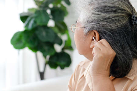 Elderly Asian women use cotton buds to wipe their earwax. The concept of health care of seniors. The danger of earwax obstructionの写真素材