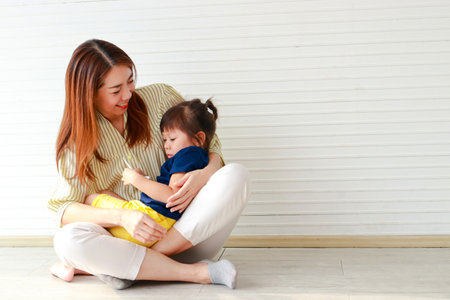cute mother and daughter Hugging and teasing each other sitting on the floor of the house. Family concept. single mother. copy spaceの写真素材