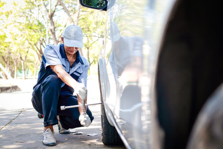 auto repair technician Changing the wheels of a car for a customer who has an accident with a broken tire on the road. Transportation concept. service businessの写真素材