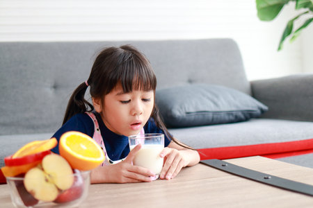 Cute little Asian girl drinking milk. Children are forced to drink milk. Concept of healthy food for children. healthy body careの写真素材