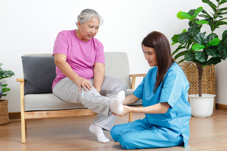 Asian female doctor doing physical therapy for elderly people with leg pain. Concept of physical rehabilitation for the elderly. Elderly health care and physical therapy centerの写真素材