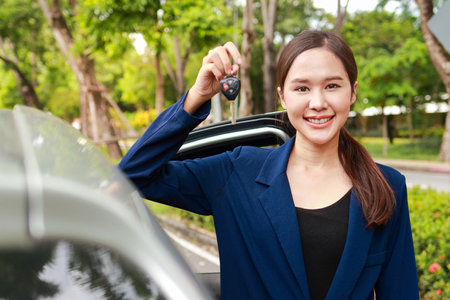 Beautiful Asian woman holding the keys to her new car. Happy smile. The concept of transportation. beautiful saleswoman holding car keysの写真素材