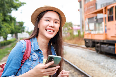 Portrait of a beautiful Asian woman with a beautiful smile enjoying a train journey. She was waiting for the train at the station. Tourism concept. Traveling by train in Thailandの写真素材