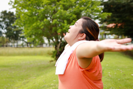 Asian fat woman smiling happy Stretching arms outdoor exercise to lose weight Make your body healthy. health care sports conceptの写真素材