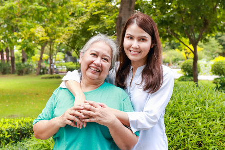 portrait of mother and daughter standing together in the park They both smiled happily. Family concept. Carers for the elderly in retirement age. health care centerの写真素材