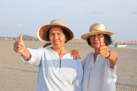 Elderly society in retirement age. two elderly women happy to go to sea and thumbs up for liking. retirement tourismの写真素材