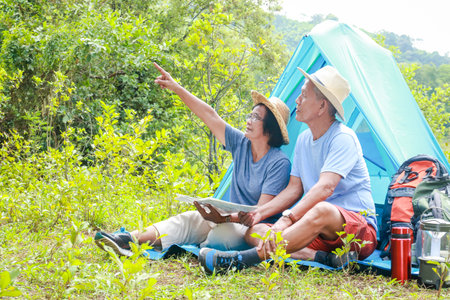 Asian elderly couple happy to travel in nature Set up a tent and camp in the forest. Tourism concept of the elderly in retirement age. Tourists and travelers trekkingの写真素材