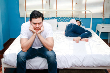 Husband quarrels with his wife He was sitting on the bed with his feet on his chin. concept of family problemsの写真素材