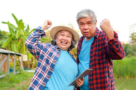 Asian elderly farmer holding a tablet Used to control the solar panel. to use electricity in agriculture. Solar system. concept of using modern agricultural technologyの写真素材