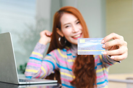 Asian woman sitting at work and holding credit card happy smile online shopping conceptの写真素材